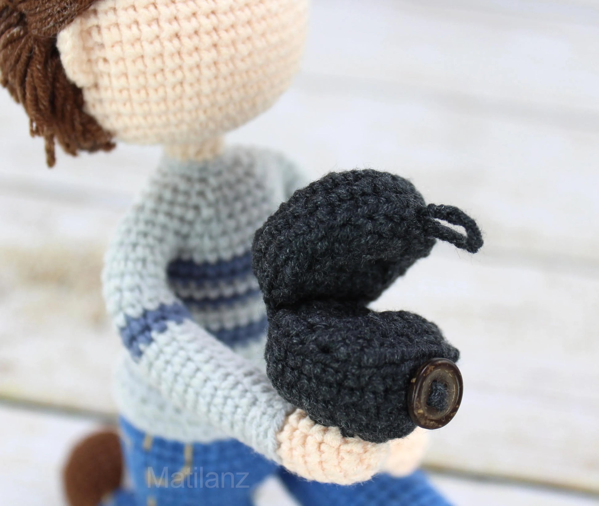 A handmade crocheted doll with a striped sweater and black boot, perfect for personalized gifts.