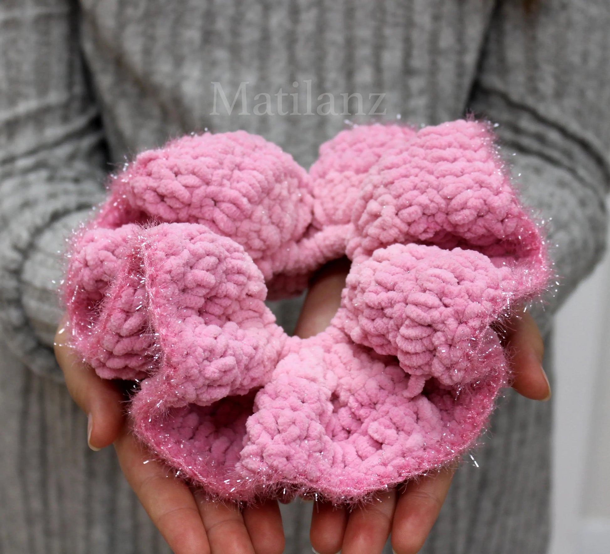 Soft, pink, crocheted scrunchies with a fluffy texture and subtle sparkle.