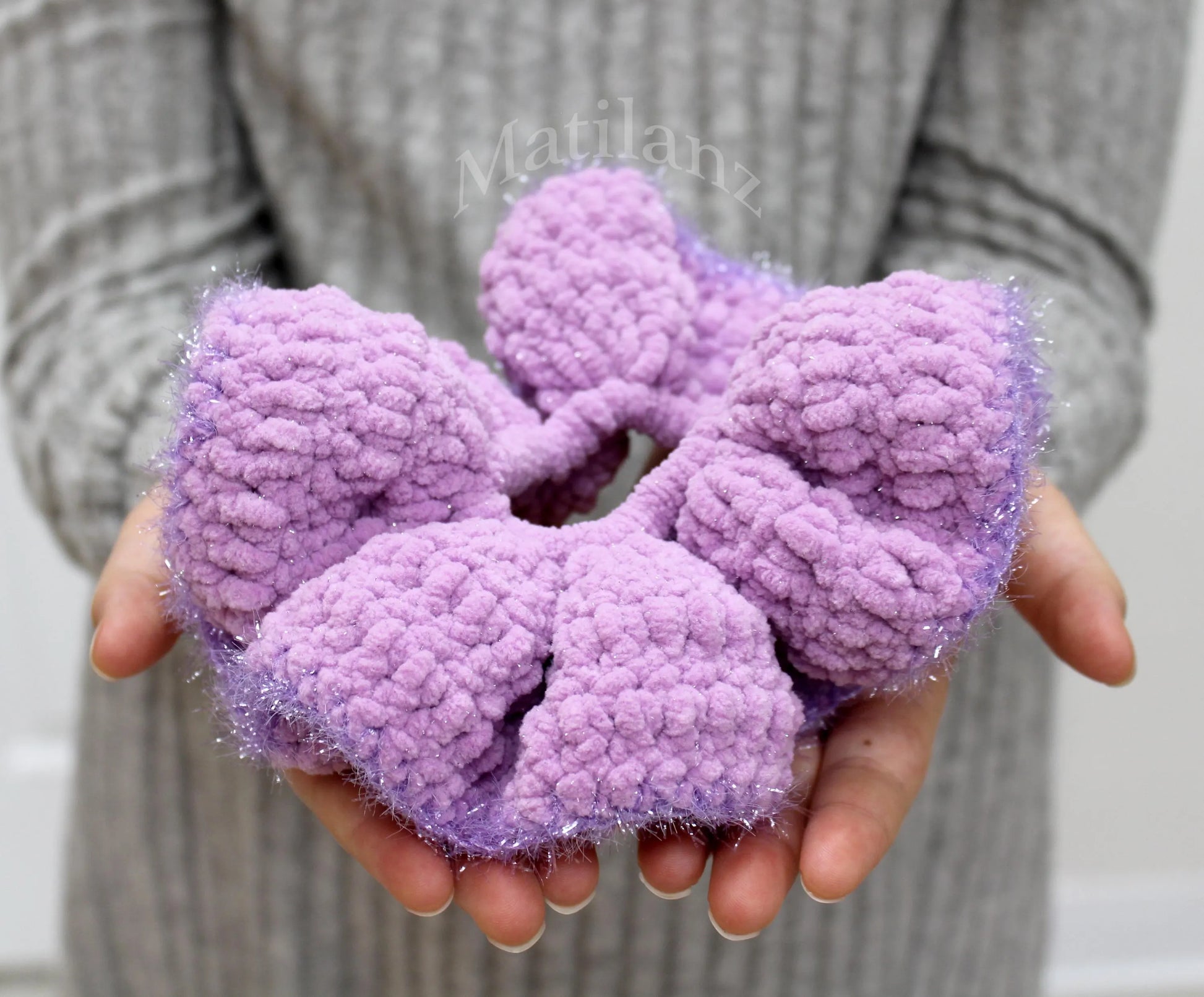 Soft, lavender-colored scrunchies with a fluffy texture and subtle sparkle.