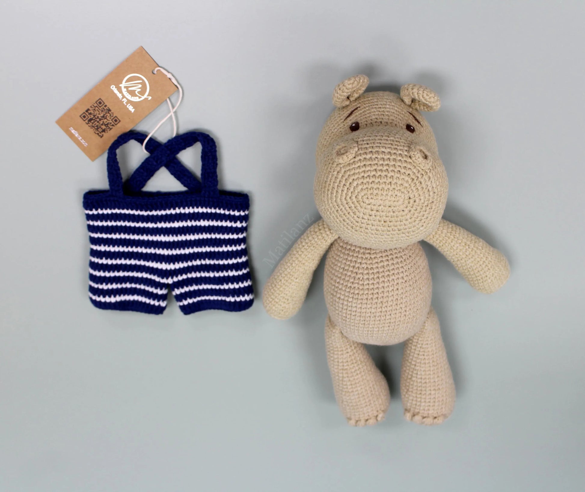 Crocheted beige hippo plushie paired with blue and white striped knit swimsuit.