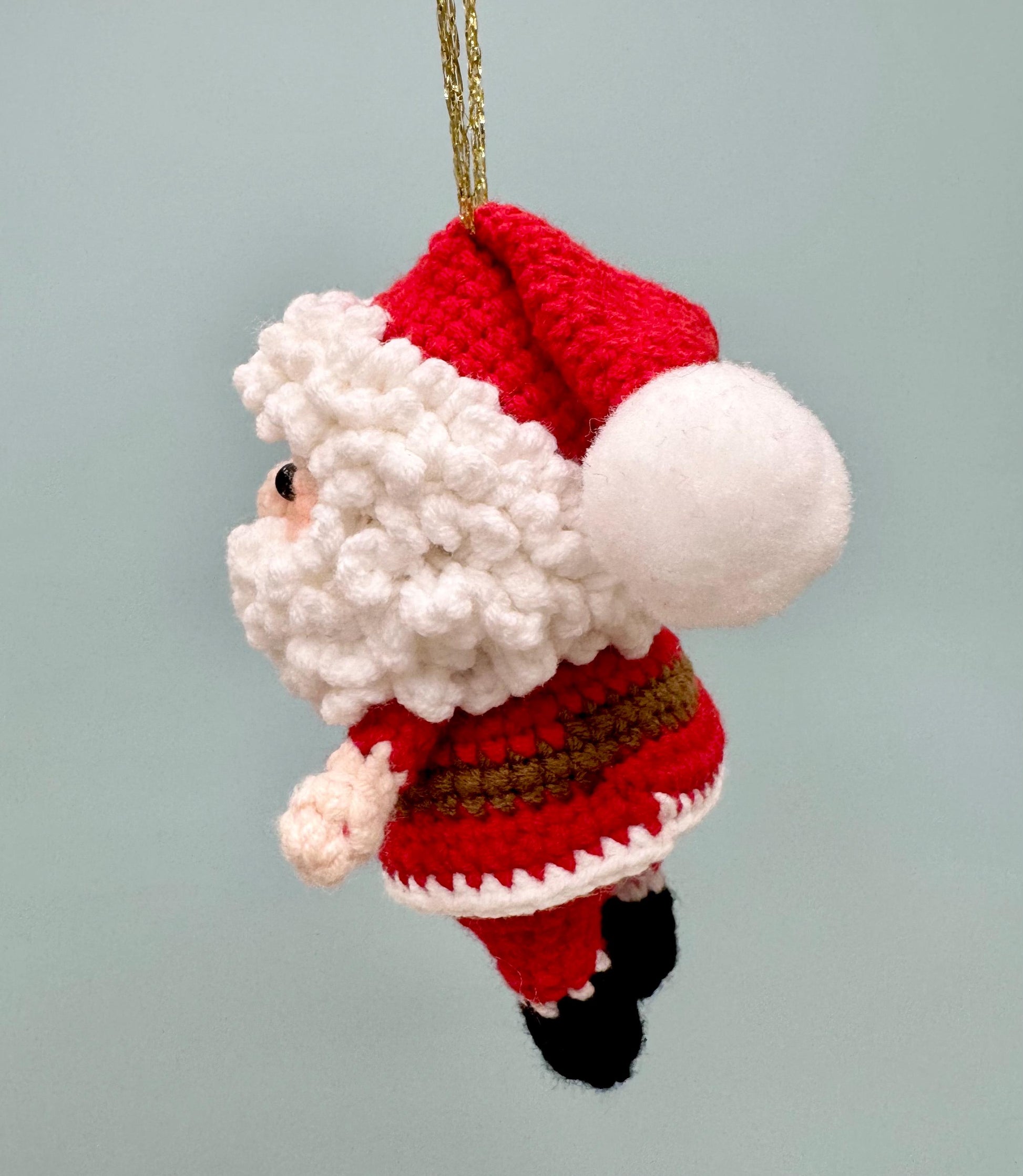 Crochet Santa Claus ornament with a red suit, white beard, and gold hanging string.