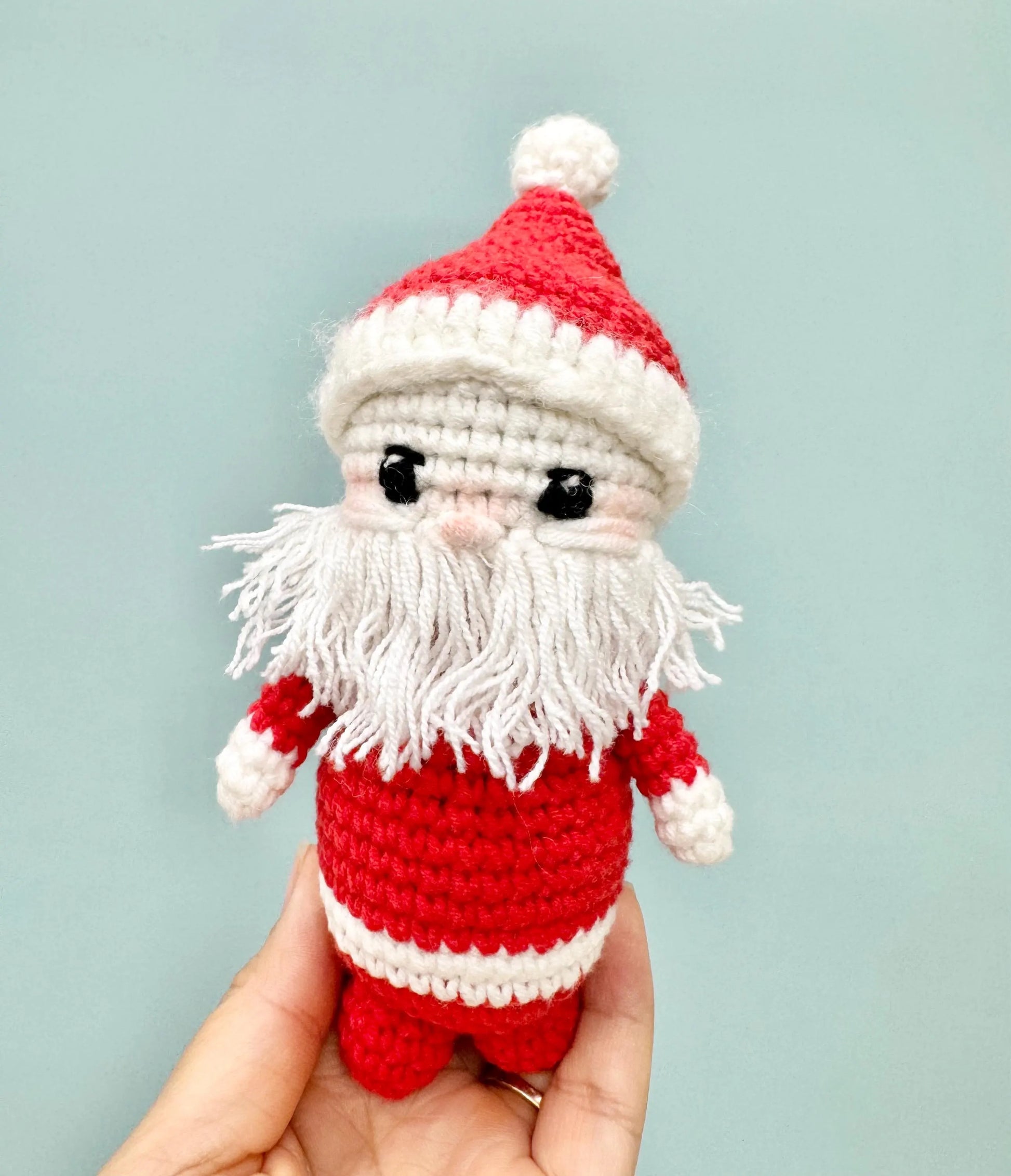 Handmade crochet Santa Claus ornament with a red and white outfit, fluffy white beard, and a cheerful expression.