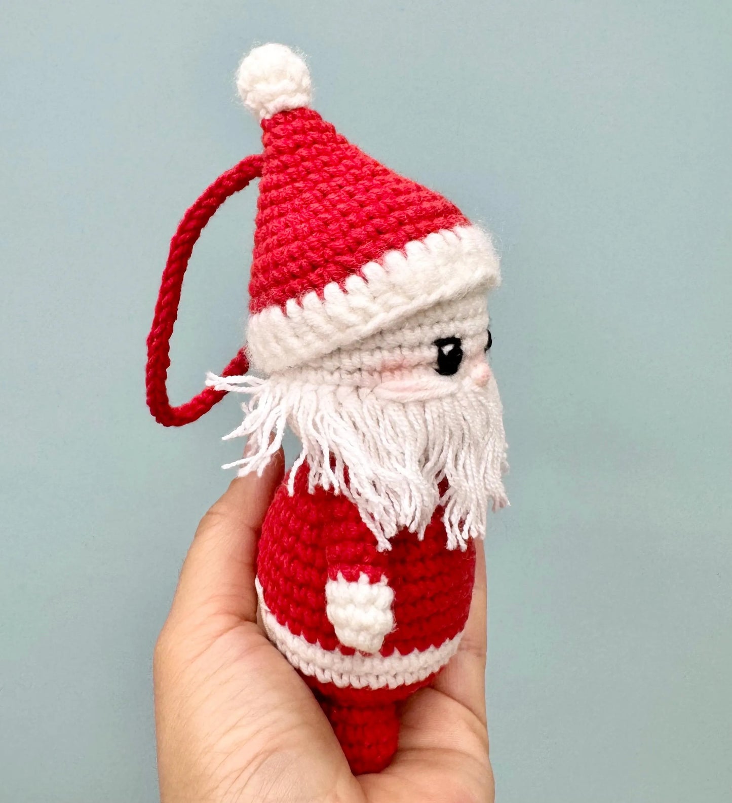 Handmade crochet Santa Claus ornament with a red hat, white beard, and festive details.
