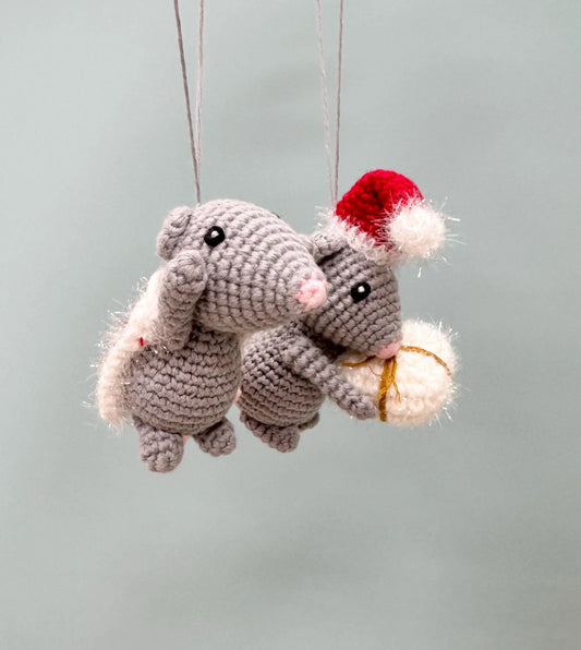 Crochet mouse ornament in gray, wearing a red Santa hat and holding a white gift, perfect for Christmas trees.