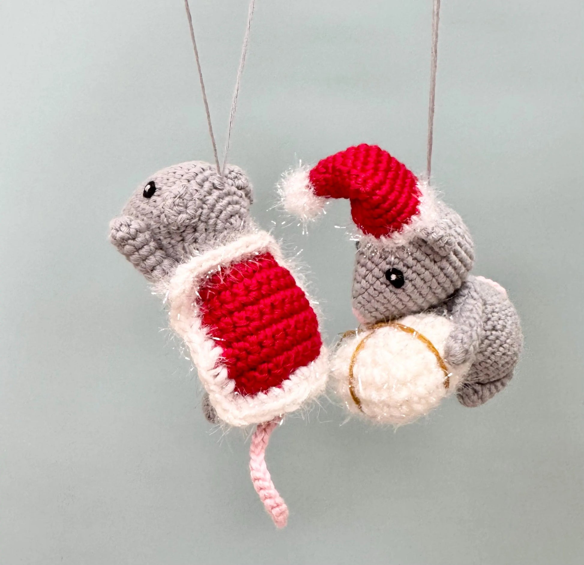 Crochet mouse ornament holding a red present, wearing a Santa hat, perfect for Christmas decorating.