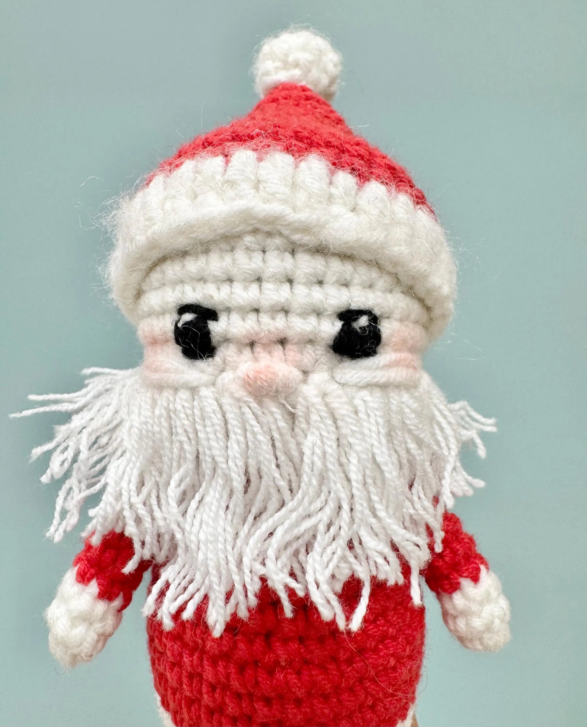 Handmade crochet Santa Claus ornament with a red and white outfit, fluffy white beard, and cheerful expression.