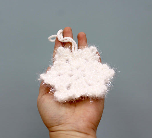A fluffy white crochet snowflake Christmas ornament with a loop for hanging.