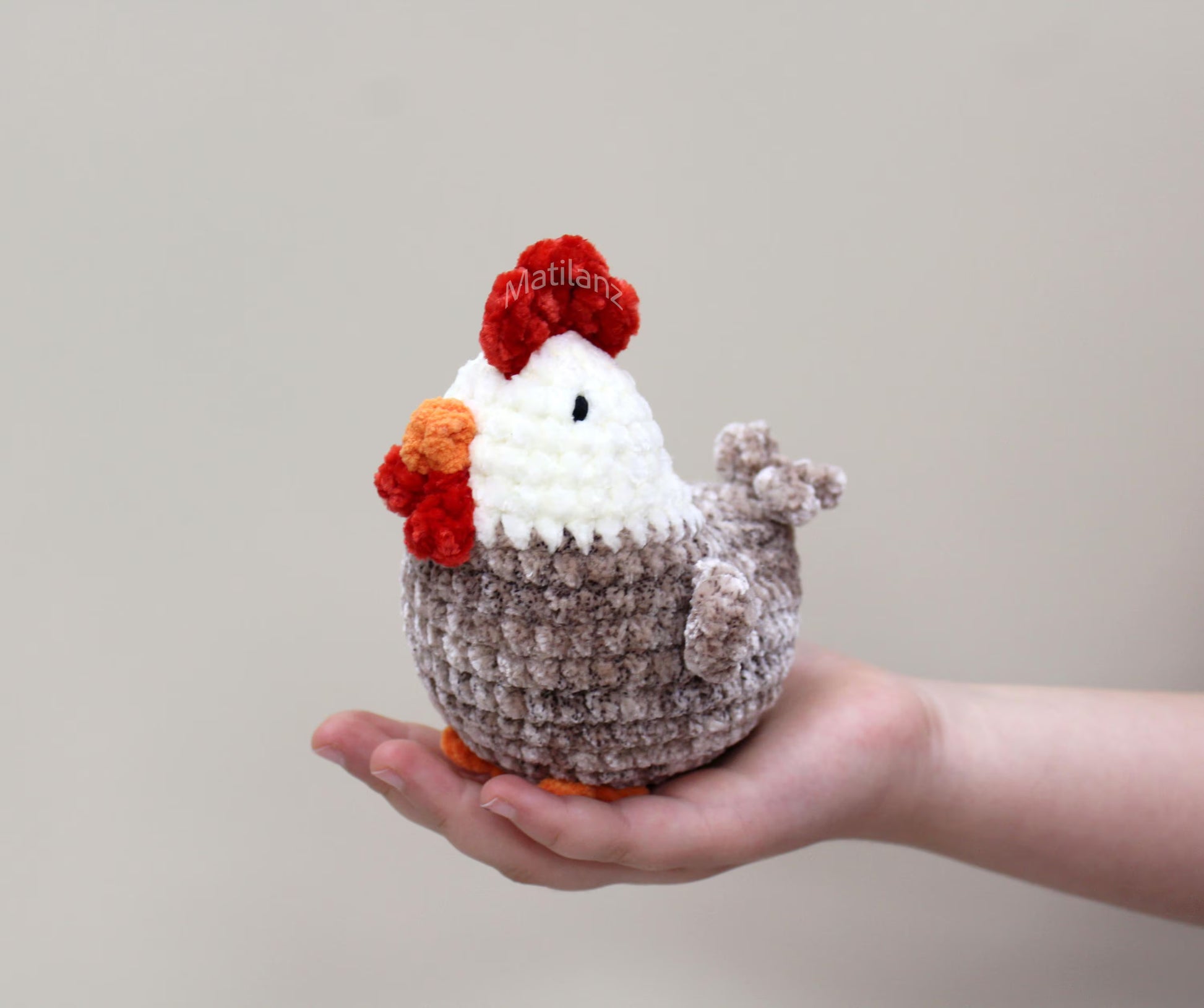 Handmade crochet chicken plushie with white face, red comb, and orange beak.